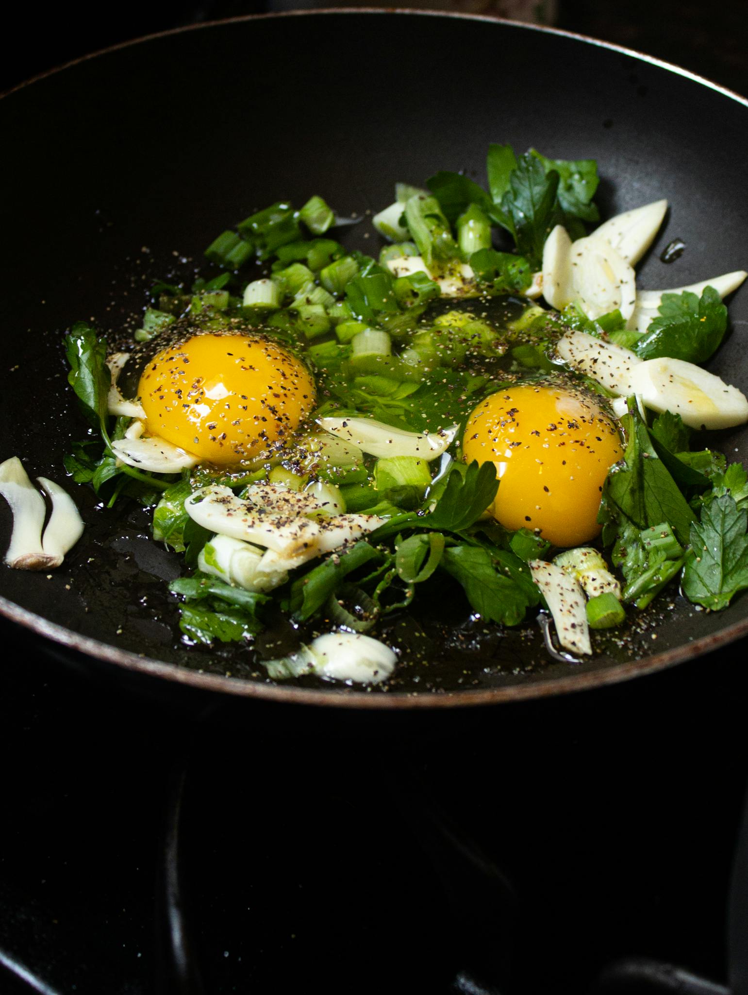 A vibrant close-up of fresh eggs and herbs frying in a skillet, perfect for a healthy breakfast.