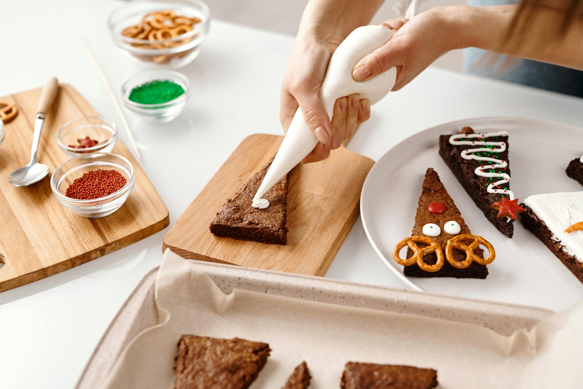Hands decorating festive Christmas cookies with icing and sprinkles in a joyful holiday preparation setting.