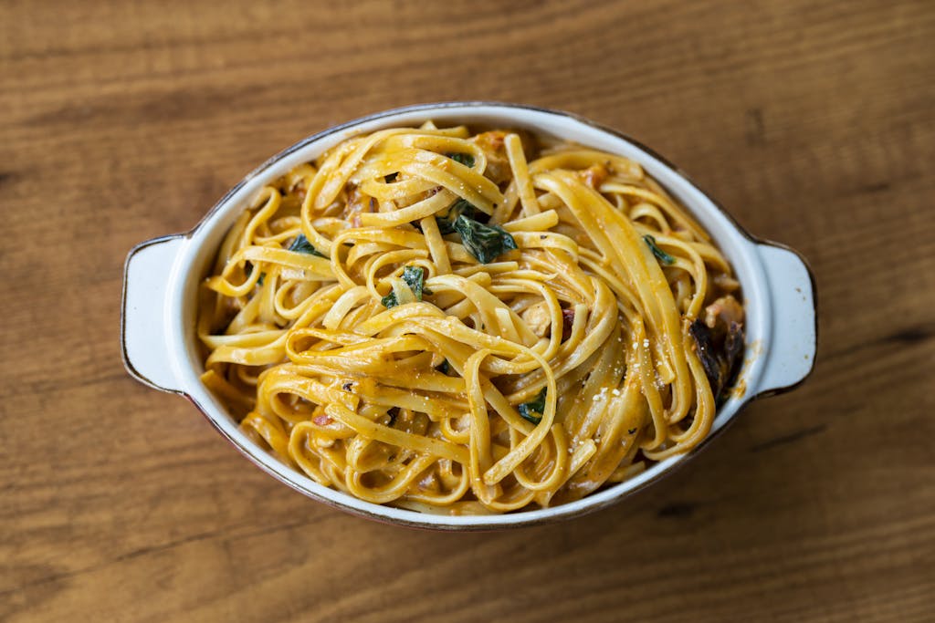 Top view of a creamy pasta dish with spinach in a white dish, perfect for dinner.