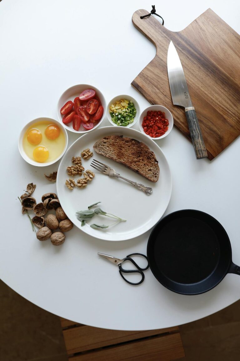 Top view of fresh breakfast ingredients, including eggs and vegetables, on a rustic table setting.